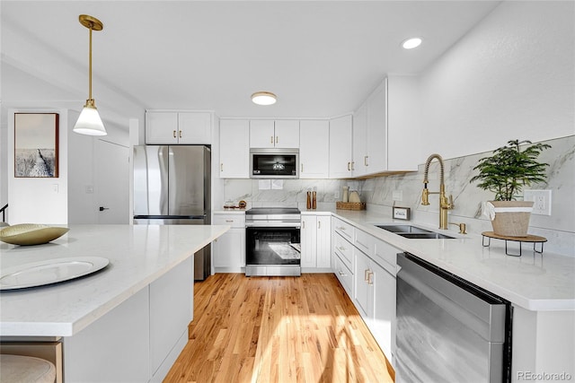 kitchen featuring appliances with stainless steel finishes, sink, pendant lighting, white cabinets, and light stone countertops