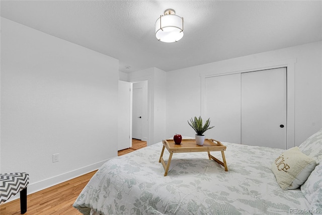 bedroom with a textured ceiling, a closet, and hardwood / wood-style floors