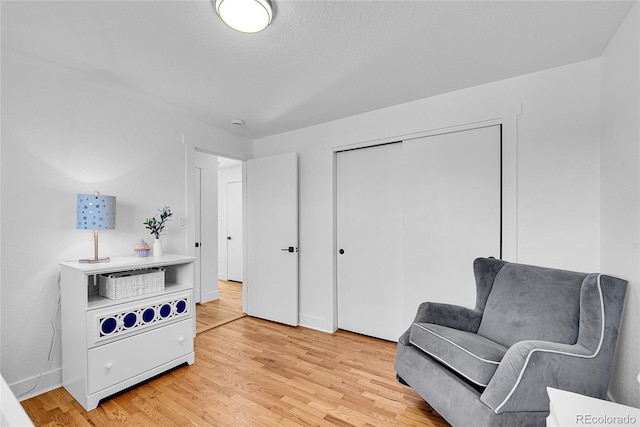 living area featuring light wood-type flooring and a textured ceiling