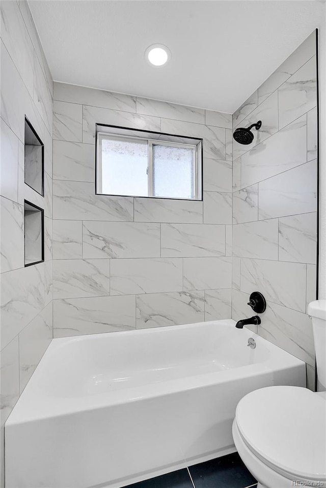 bathroom featuring toilet and tiled shower / bath