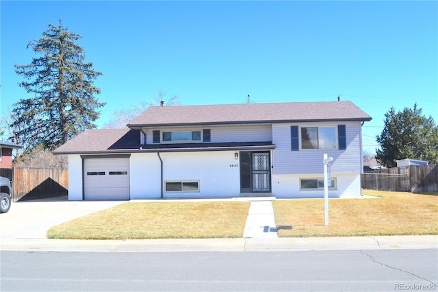 raised ranch with an attached garage, a front yard, and fence