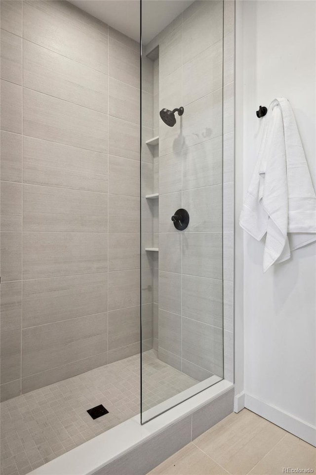 bathroom with tile patterned flooring and a tile shower