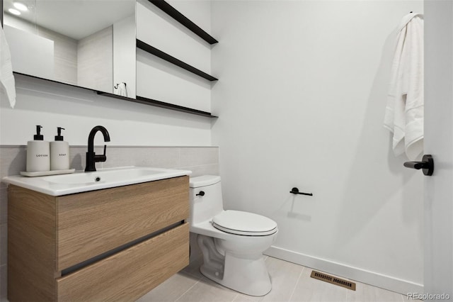 1601 Park Ave Unit 216, Denver, CO 80218 - half bath featuring tile patterned floors, toilet, vanity, tile walls, and baseboards