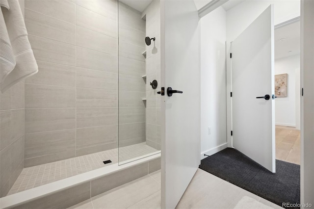 bathroom with tile patterned flooring and a tile shower