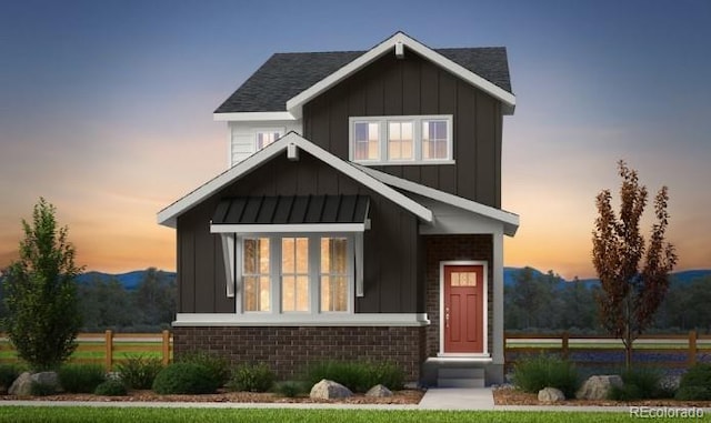 view of front of home with a standing seam roof, board and batten siding, and brick siding