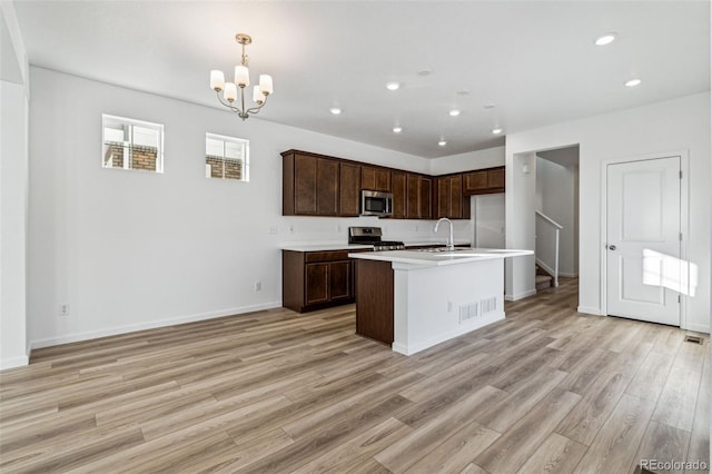 kitchen featuring recessed lighting, light countertops, an inviting chandelier, appliances with stainless steel finishes, and light wood-type flooring