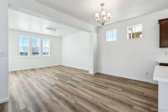 unfurnished living room with baseboards, an inviting chandelier, and wood finished floors