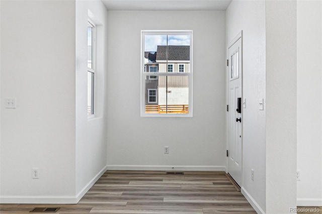 empty room with visible vents, baseboards, and wood finished floors