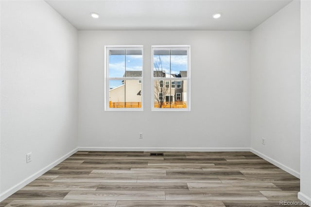 unfurnished room featuring recessed lighting, wood finished floors, and baseboards