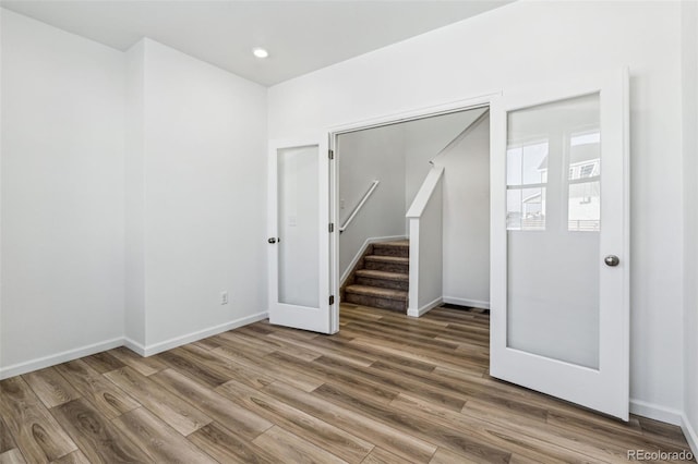 unfurnished room with baseboards, stairway, wood finished floors, and recessed lighting