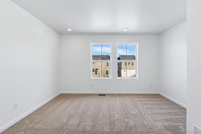 spare room with visible vents, carpet flooring, a textured ceiling, and baseboards