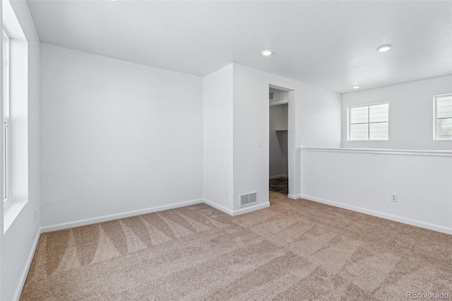 empty room with carpet, visible vents, baseboards, and recessed lighting