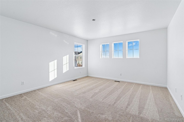 carpeted empty room with visible vents, baseboards, and a textured ceiling