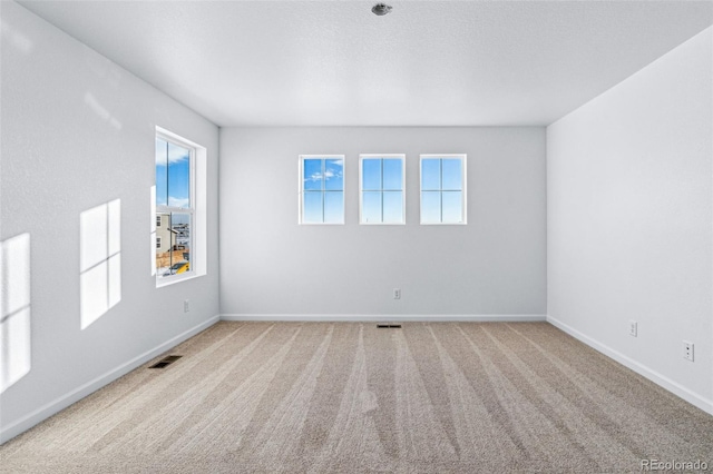 carpeted spare room with baseboards and visible vents