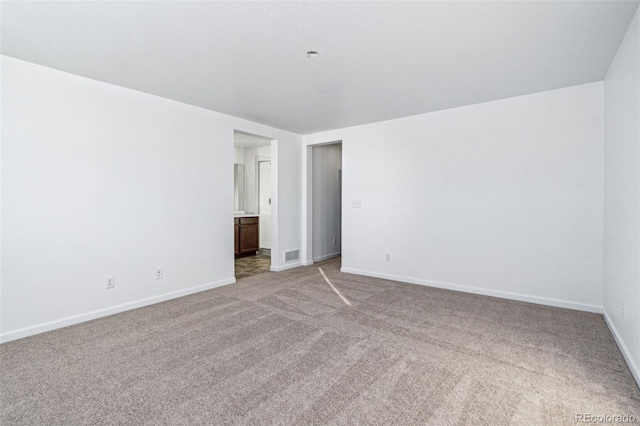 spare room with carpet floors, baseboards, and visible vents