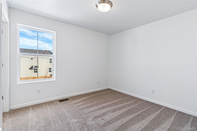 empty room with carpet floors, visible vents, and baseboards