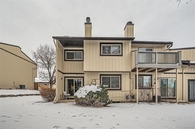 snow covered house featuring cooling unit and a balcony