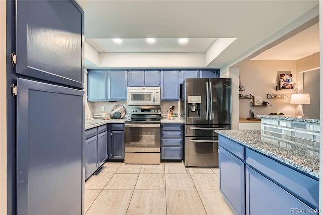 kitchen featuring light stone countertops, stainless steel appliances, blue cabinetry, a raised ceiling, and light tile patterned flooring