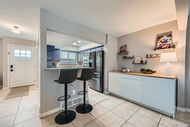 kitchen featuring light stone counters, light tile patterned floors, appliances with stainless steel finishes, and kitchen peninsula