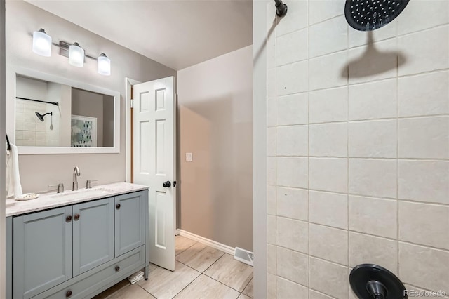 bathroom featuring vanity, tiled shower, and tile patterned flooring