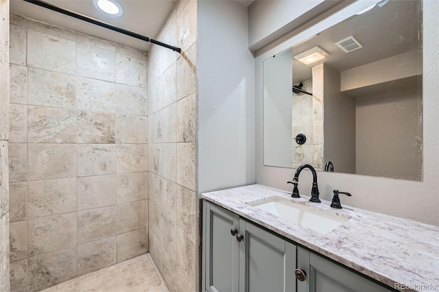 bathroom featuring tiled shower and vanity