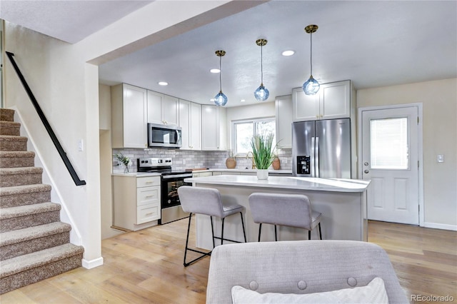 kitchen featuring white cabinets, a kitchen island, light wood-type flooring, and appliances with stainless steel finishes