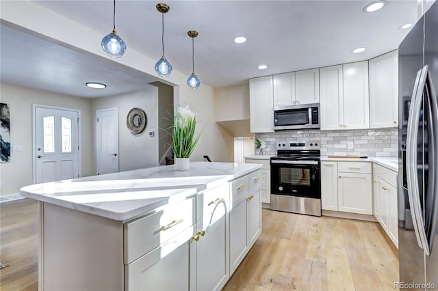 kitchen with decorative light fixtures, white cabinetry, stainless steel appliances, and light hardwood / wood-style flooring