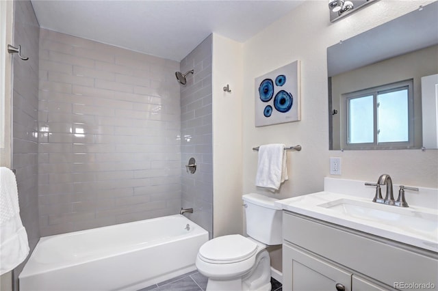 full bathroom with tiled shower / bath, tile patterned floors, vanity, and toilet