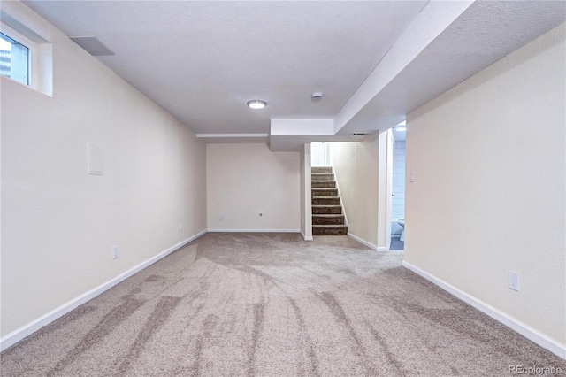 basement featuring light carpet and a textured ceiling