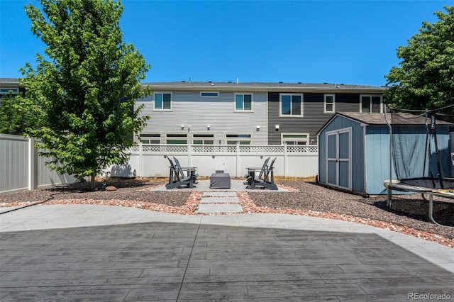 4695 Andes St, Denver, CO 80249 - back of property featuring a trampoline, a patio area, a storage unit, and a fenced backyard