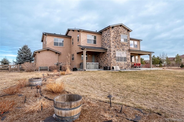 back of house with a lawn, a patio, and a hot tub