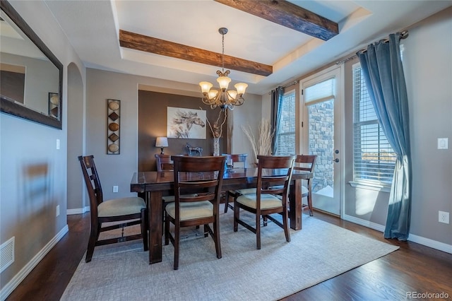 dining area with a raised ceiling, dark hardwood / wood-style flooring, and a chandelier