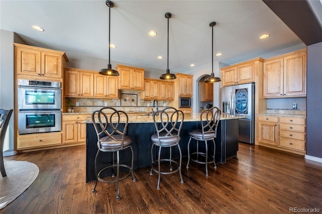 kitchen featuring pendant lighting, an island with sink, appliances with stainless steel finishes, and tasteful backsplash