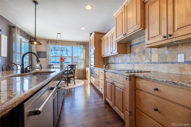 kitchen featuring light stone countertops, sink, dark wood-type flooring, stainless steel appliances, and decorative light fixtures