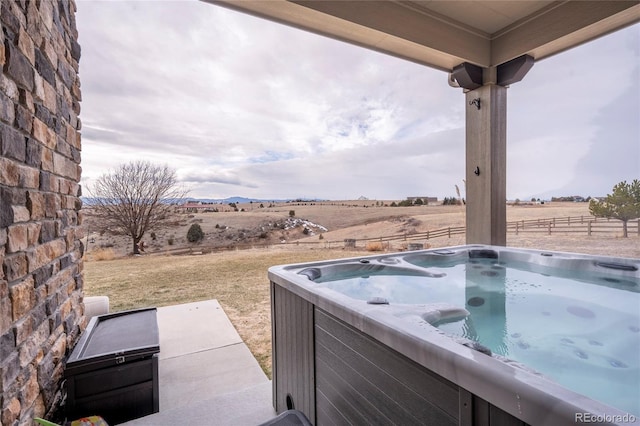 view of patio with a rural view and a hot tub