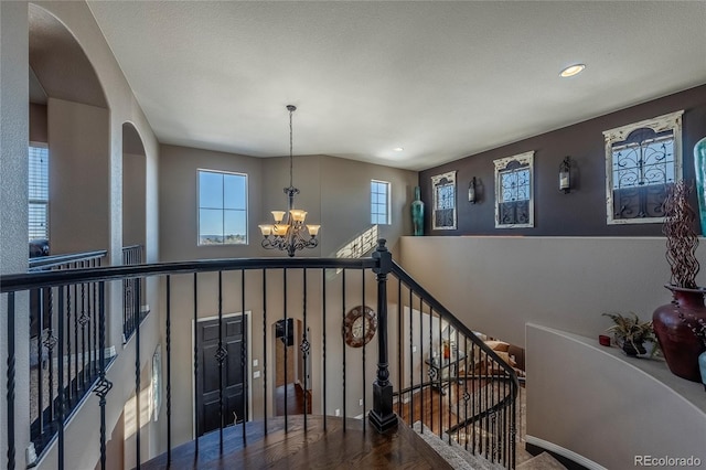 staircase with hardwood / wood-style flooring and an inviting chandelier