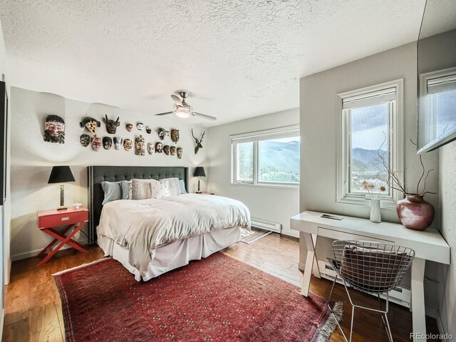 1370 Sandstone Dr Unit 12, Vail, CO 81657 - bedroom featuring a textured ceiling, wood finished floors, a baseboard heating unit, and a ceiling fan