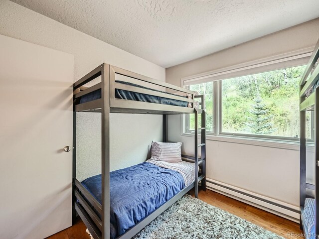 1370 Sandstone Dr Unit 12, Vail, CO 81657 - bedroom featuring a baseboard heating unit, wood finished floors, and a textured ceiling