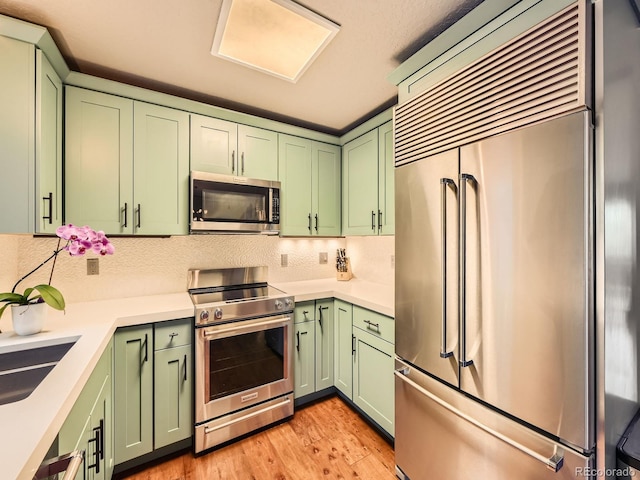 1370 Sandstone Dr Unit 12, Vail, CO 81657 - kitchen featuring appliances with stainless steel finishes, green cabinetry, light countertops, and tasteful backsplash