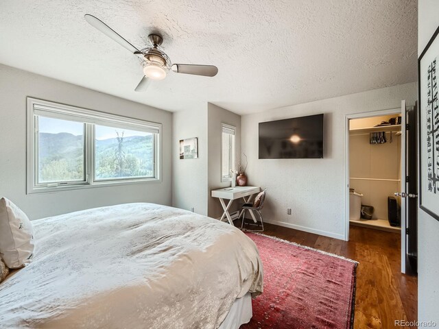 1370 Sandstone Dr Unit 12, Vail, CO 81657 - bedroom featuring wood finished floors, a textured ceiling, a walk in closet, a closet, and a ceiling fan