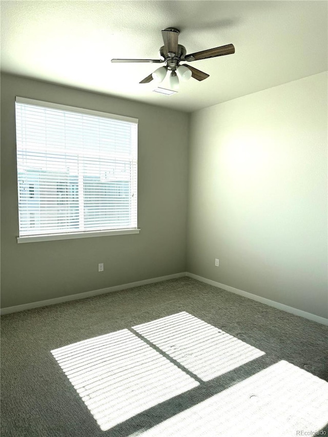 empty room featuring ceiling fan and dark colored carpet