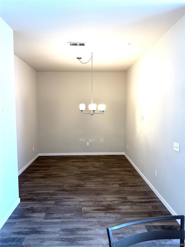 unfurnished dining area featuring a notable chandelier and dark wood-type flooring