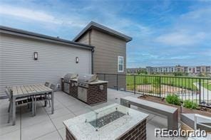 view of patio with area for grilling and a fire pit