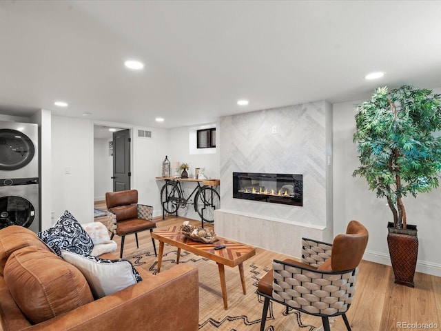 living room featuring stacked washer and dryer, light wood-type flooring, and a fireplace