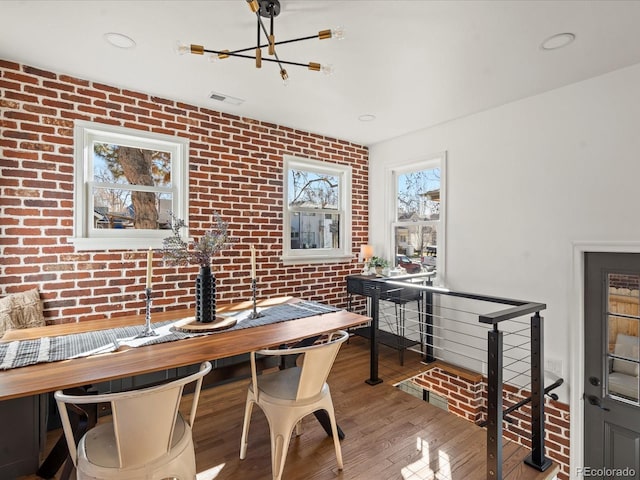 dining space with hardwood / wood-style flooring and brick wall