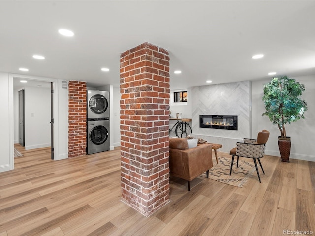 living room featuring a high end fireplace, light hardwood / wood-style floors, and stacked washer and clothes dryer