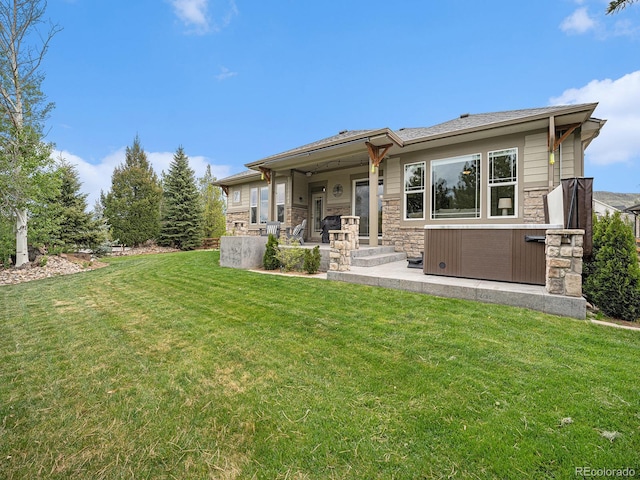 19379 W 57th Pl, Golden, CO 80403 - rear view of property featuring a hot tub, a yard, and stone siding