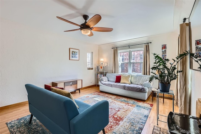 living area featuring a ceiling fan, wood finished floors, and baseboards