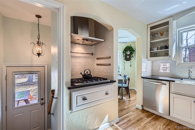 kitchen featuring stainless steel appliances, white cabinets, glass insert cabinets, dark countertops, and light wood-type flooring