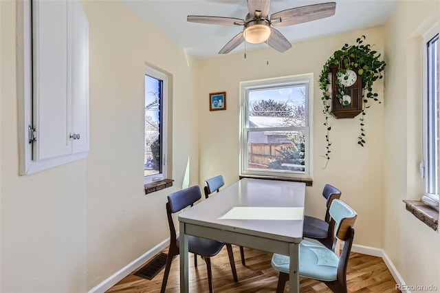 dining space featuring visible vents, ceiling fan, baseboards, and wood finished floors